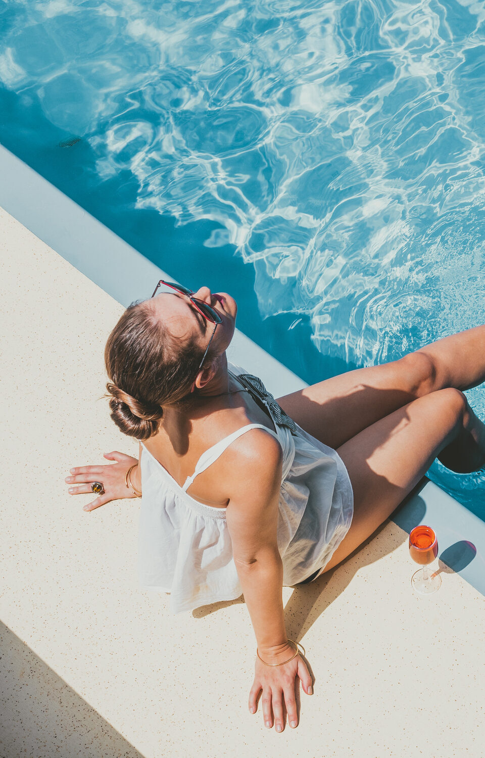 A woman sits by her home pool, enjoying the experience. Marklynn Pools offers expert pool services to make owning your own pool a breeze.